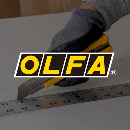 Olfa snijmes met liniaal op tafel, hand met handschoen in beeld