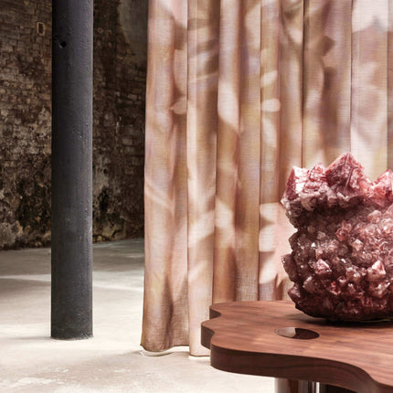 Gordijnstof Cosima van Kendix, De Ploeg, in een modern interieur met zacht natuurlijk licht en een roze siersteen op houten tafel.