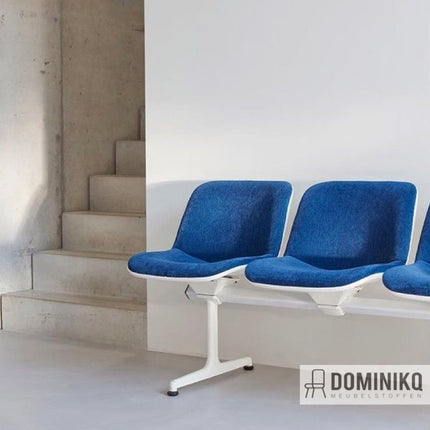 Moderne blauw gestoffeerde zitplaatsen in een minimalistische ruimte met betonnen trappen, ontworpen door Aristide.