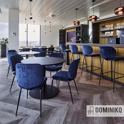 Alt Tag: Moderne bar met blauwe velours stoelen in een stijlvolle ruimte, bekleed met Aristide - Lobo - 710 Peacock stof.