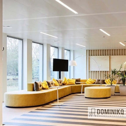 Stijlvolle lounge met gele velours bank en moderne inrichting, ruime ramen met uitzicht. Perfect voor een elegante en rustige sfeer.