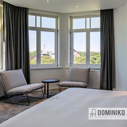 Modern interieur met Aristide Troy stof bank en gordijnen in een lichte kamer met grote ramen en uitzicht.