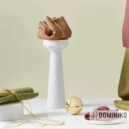 Bruine en groene Camira Fabrics Rivet meubelstoffen elegant gepresenteerd op marmeren standaarden met gouden accenten.