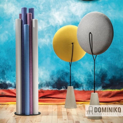 Abstracte opstelling van Camira Fabrics Synergy 170 stoffen op pijlers, in diverse kleuren tegen een kunstzinnige achtergrond.