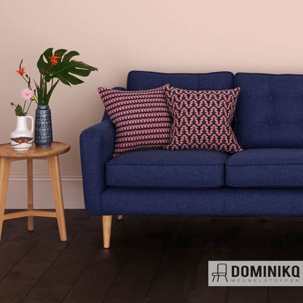 Donkerblauwe bank met Camira Fabrics kussens in driekleurige tweed en bloempot op houten tafel.