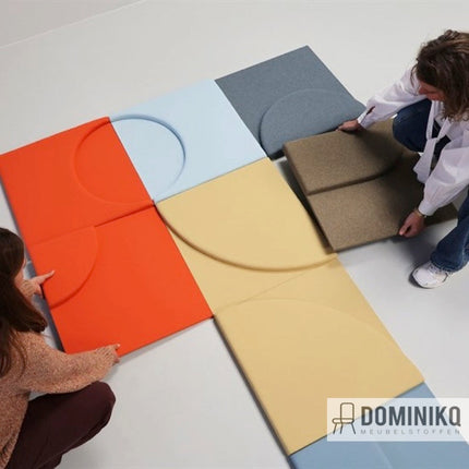 Twee personen leggen kleurrijke Step Melange Schermstoffen op een vloer als creatieve ruimteverdeler.