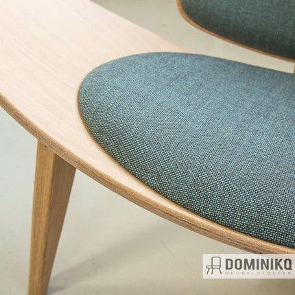 Stijlvolle stoel met minimalistische Scandinavische wolbekleding in blauw-groen, met micro-geometrisch ruitpatroon en houtaccenten.