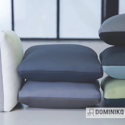 Een stapel kussens bekleed met Gabriel - Rhythm stof in diverse kleuren, met een caleidoscopisch patroon en brandvertragende eigenschappen.