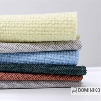 Verschillende stapels van Gabriel's Nobel bekledingsstof in diverse kleuren en texturen, perfect voor luxueuze zitmeubelen.