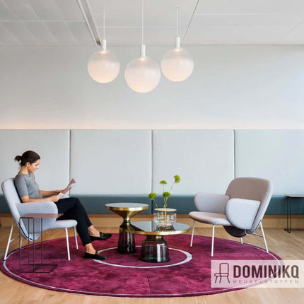 Moderne zithoek met Kvadrat Uniform Melange stoffen stoelen, glazen tafels en sierverlichting op wijnrode tapijt.