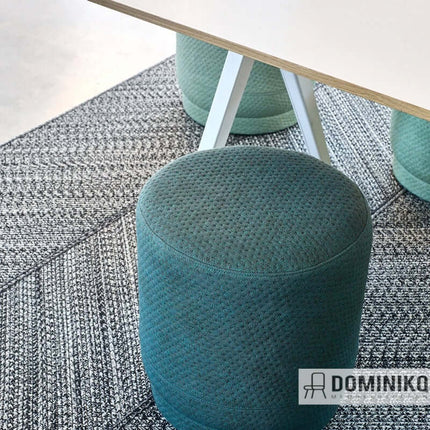 Kvadrat Febrik Rumor stof op groene poef, duurzaam en flexibel voor stofferingsprojecten, met grafisch patroon en pixelachtige textuur.