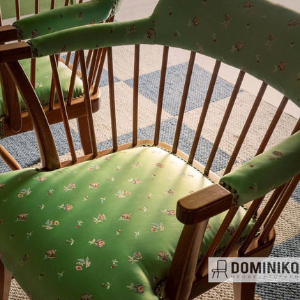 Houten stoel met groene bekleding en bloemmotief, op een blauwe en beige geruite vloer.