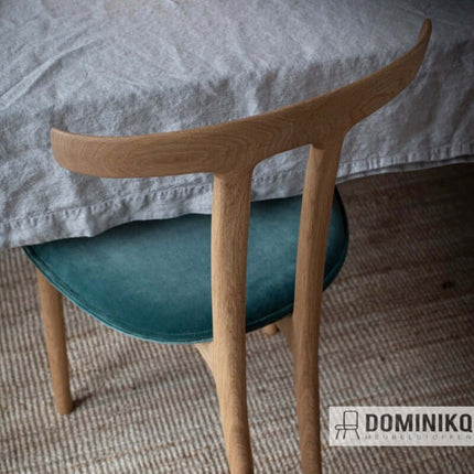 Houten stoel met groene zitting en linnen tafelkleed in een stijlvol interieur.