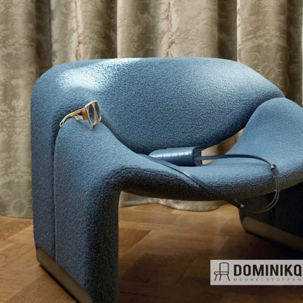 Moderne stoel met zachte geweven wollen bouclé bekleding in diepblauw, naast een gordijn met elegante textuur.