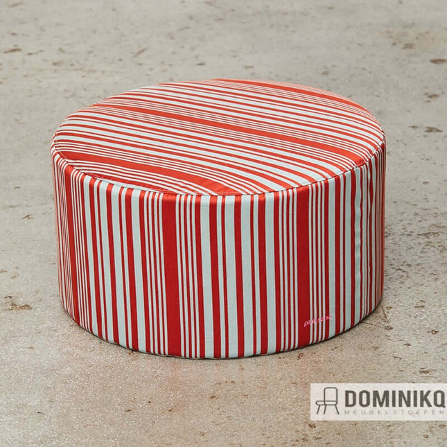 Red and white striped round ottoman on a textured floor.