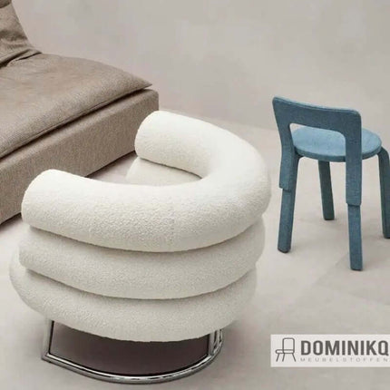 Moderne woonkamer met crème kleurige bouclé stoel en blauwe eetkamerstoel op beige vloer.