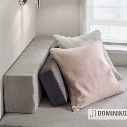 Grijze hoekbank met zachte kussens in pastelkleuren, gestyled voor een moderne woonkamer.