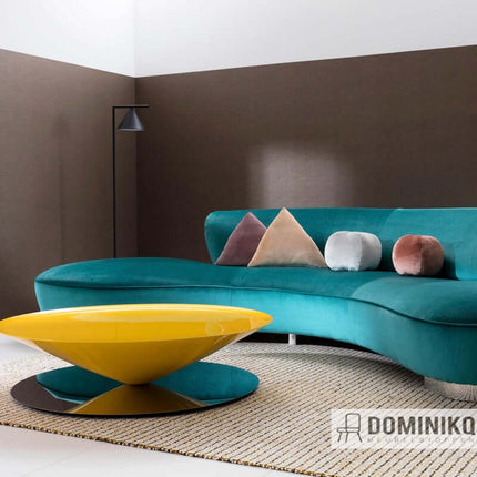 Moderne woonkamer met turkoois fluwelen bank, gele salontafel en kleurrijke kussens.
