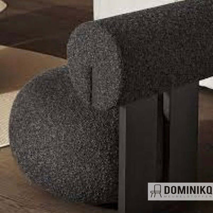 Elegante bouclé meubelstof Kvadrat Sahco Zero, met pareleffect en luxe Parijse couture uitstraling, in donkere kleur op stoel.