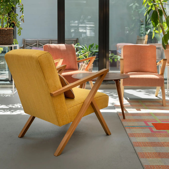 Moderne woonkamer met kleurrijke fauteuils bekleed met Vescom Fuga stof, decoratief en subtiele textuur in zonnige setting.
