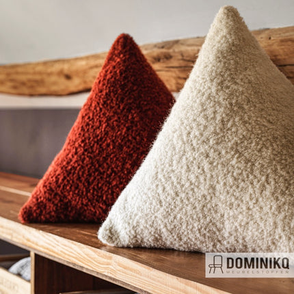 Driehoekige kussens bekleed met Casal Flocon bouclé meubelstof in rood en crème, op een houten plank