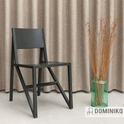 Moderne zwarte stoel voor beige gordijnen, decoratieve vaas met droogbloemen, Dominikq meubelstoffen design, natuurlijke esthetiek.