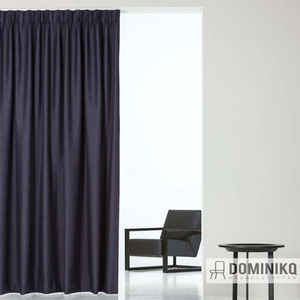 Donkerblauw gordijn van brandvertragende De Ploeg stof, elegant en functioneel in moderne kamer. Vanaf 5 meter 10% korting mogelijk.