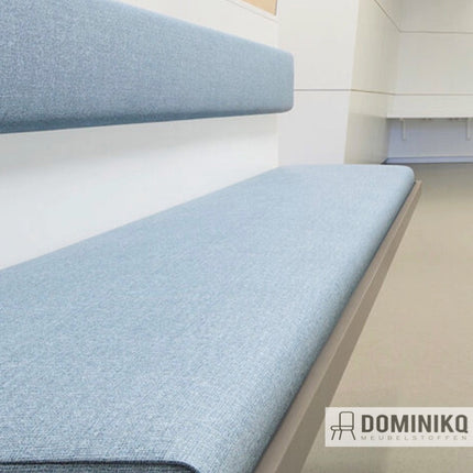 Blauwe Vescom Cyprus stoffering op bank in moderne commerciële ruimte, eigentijdse uitstraling met duurzame vinyl coating.