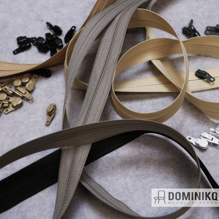 Diverse ritsen en ritstrekkers van Dominikq in beige en bruin op een grijze ondergrond, ideaal voor op maat gemaakte kussens.